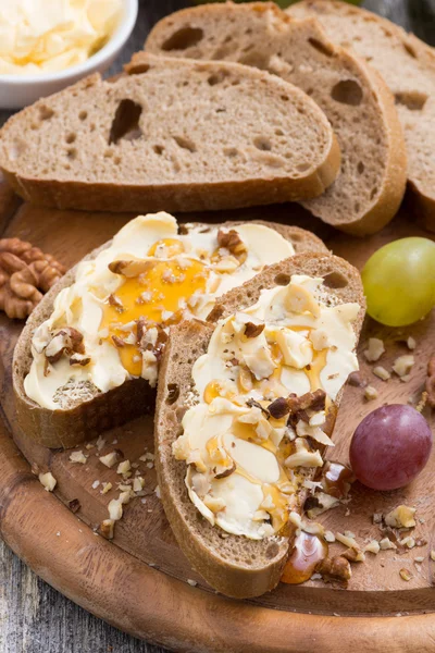 Bröd med smör, honung och nötter, vertikal, närbild — Stockfoto