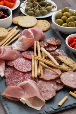 Çeşitli et aperatifler, sosis ve dikey bir kara tahta üzerinde turşu