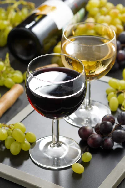 Red and white wine in glasses, fresh grapes in the background — Stock Photo, Image