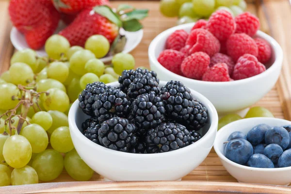 Bayas frescas y uvas verdes en una bandeja de madera — Foto de Stock