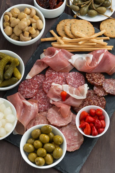 Snack, salsicce e sottaceti assortiti su una lavagna — Foto Stock