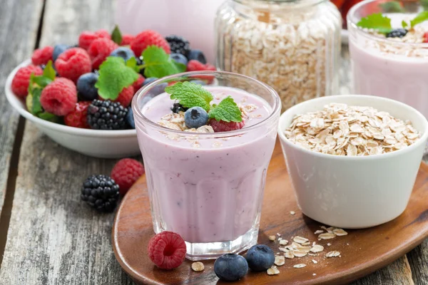 ahşap masa üzerinde bir bardak yulaf ezmesi ile Berry güler yüzlü