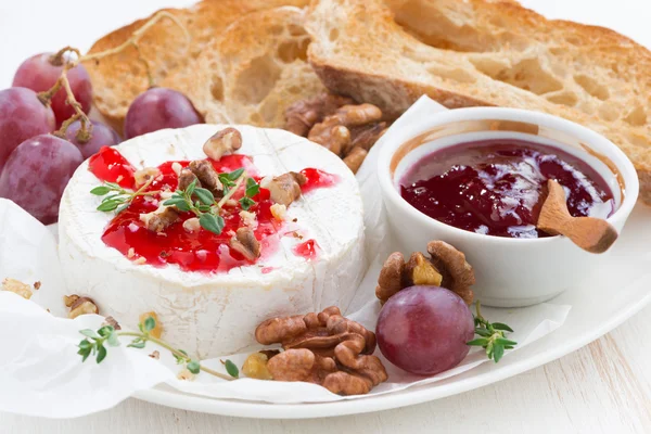 Camembert с ягодным вареньем и тостами на тарелке — стоковое фото