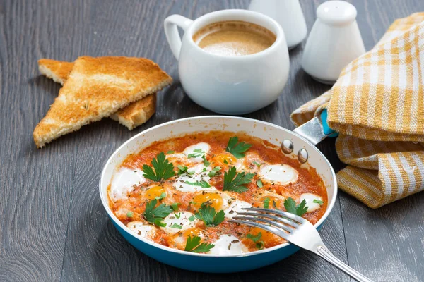 Fried quail eggs in tomato sauce with toasts in a frying pan — Stock Photo, Image