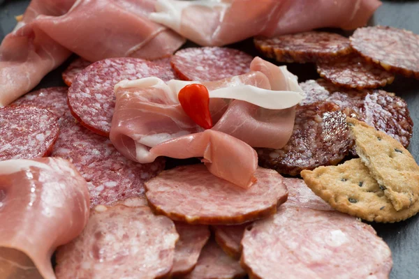 Snack, salsicce e sottaceti assortiti su una lavagna — Foto Stock