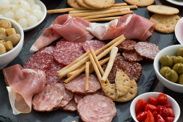 Snack di carne assortiti, salsicce e sottaceti su una lavagna — Foto Stock