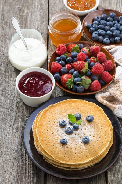 Crepes, fresh berries and jams on wooden table, vertical — Stock Photo, Image