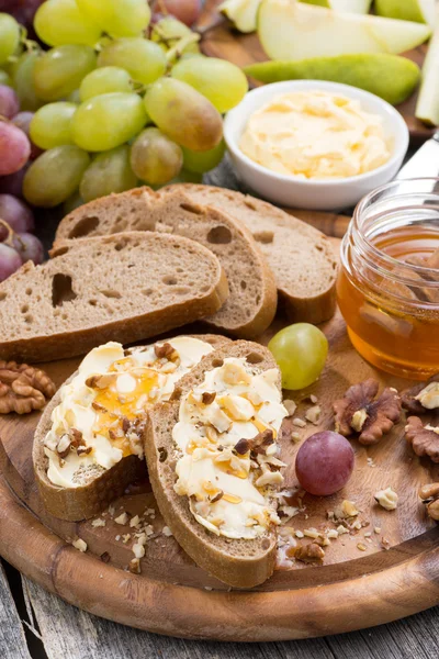 Bread with butter, honey, nuts and grapes, vertical — Stock Photo, Image