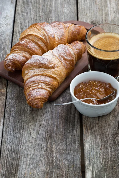 Croissants, Kaffee und Orangenmarmelade auf Holzgrund — Stockfoto