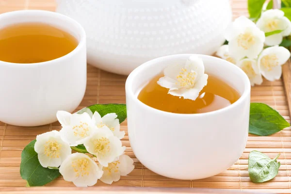 Thé au jasmin vert dans des tasses blanches et des fleurs fraîches — Photo