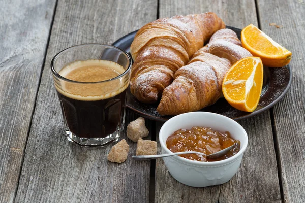 Rogaliki, espresso i dżemem pomarańczowym na drewnianym stole — Zdjęcie stockowe