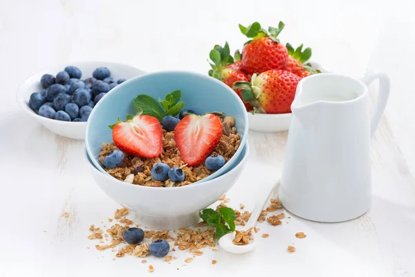 Alimentos saludables - granola, bayas frescas y leche sobre una mesa blanca —  Fotos de Stock
