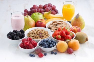 fresh berries, fruit and mueslion white wooden table