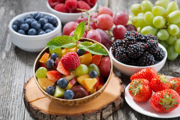 Fruit salad in a bamboo bowl and fresh berries — Stock fotografie