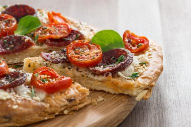 parça pizza salam ve ahşap tahta üzerinde domates ile