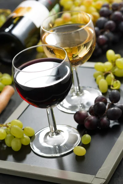 Red and white wine in glasses, fresh grapes in the background — Stock Photo, Image