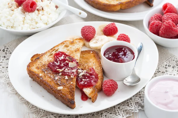 Desayuno dulce - tostadas crujientes con frambuesas, plátano y mermelada — Foto de Stock