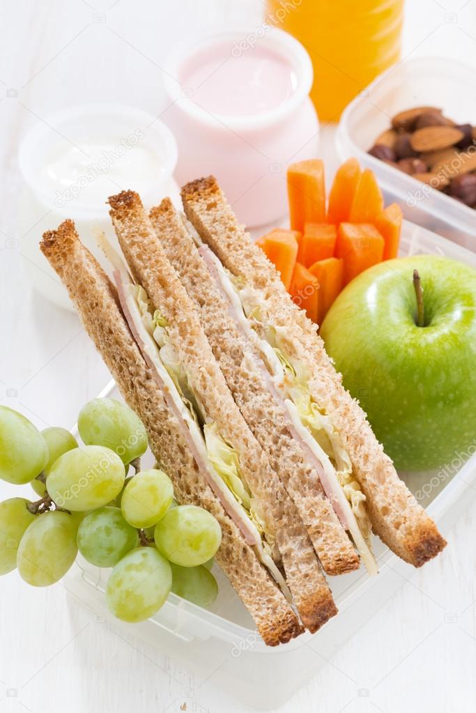 school lunch with sandwich on white wooden table, vertical
