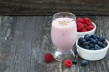 milkshake and fresh berries on the wooden background, top view