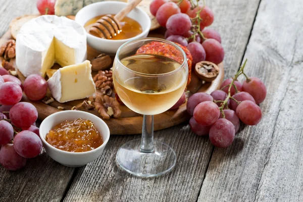 Glass of cold white wine and snacks on a wooden background — Stock Photo, Image