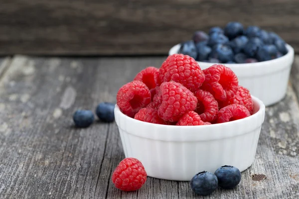 Seasonal berries - raspberries and blueberries in bowls — Stock Photo, Image