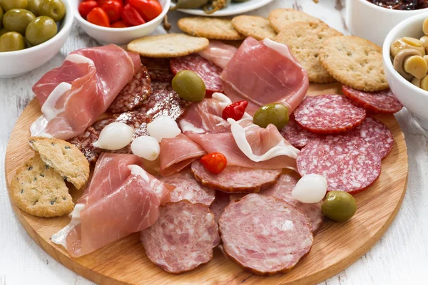 Verschiedene Fleischsnacks, Würstchen und Essiggurken auf Holzbrett — Stockfoto