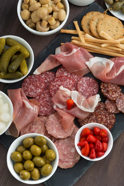 Snack, salsicce e sottaceti assortiti su una lavagna — Foto Stock
