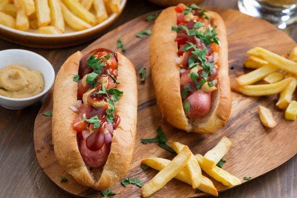 Hot dogs with tomato salsa and onions on wooden board, top view — Stock Photo, Image