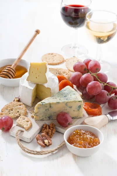Gjuten ostar, frukt och snacks på en vit trä bakgrund — Stockfoto