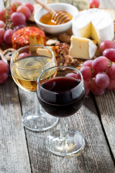 Стакан белого и красного вина, закуски на деревянном фоне — стоковое фото