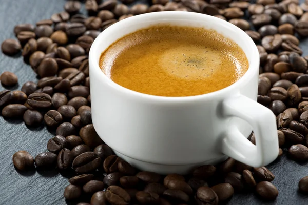 Espresso på kaffebönor bakgrund, närbild, selektiv inriktning — Stockfoto
