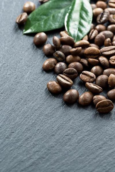 Coffee beans and leaves on dark background, space for your text — Stock Photo, Image