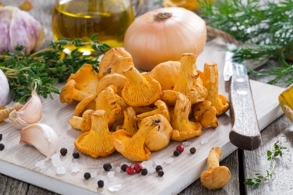 Fresh chanterelles and ingredients for cooking on wooden board — Stock Photo, Image