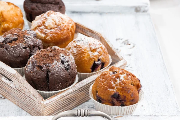 Leckere Muffins auf einem Holztablett auf weißem Hintergrund — Stockfoto
