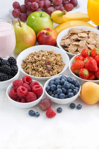 Bayas frescas, fruta y mueslion mesa de madera blanca, vertical — Foto de Stock