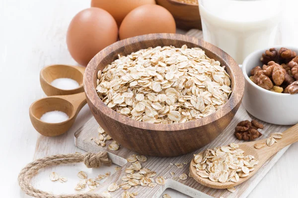 Fiocchi d'avena e ingredienti su un tavolo di legno bianco — Foto Stock