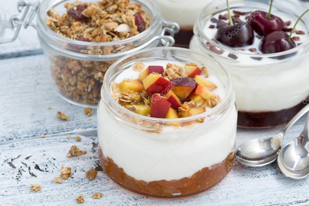 dessert with cream, peach and cherry jam in glass jars, closeup