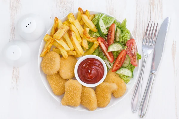 Nuggets de frango, batatas fritas e salada de legumes, vista superior — Fotografia de Stock