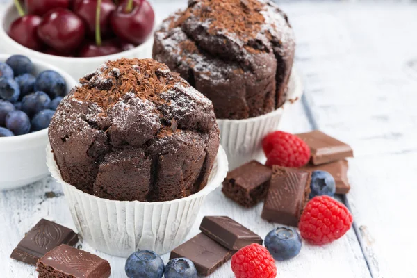 Muffins de chocolate e bagas frescas na mesa de madeira branca — Fotografia de Stock