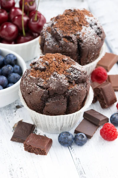 Muffins de chocolate e bagas frescas na mesa de madeira branca — Fotografia de Stock
