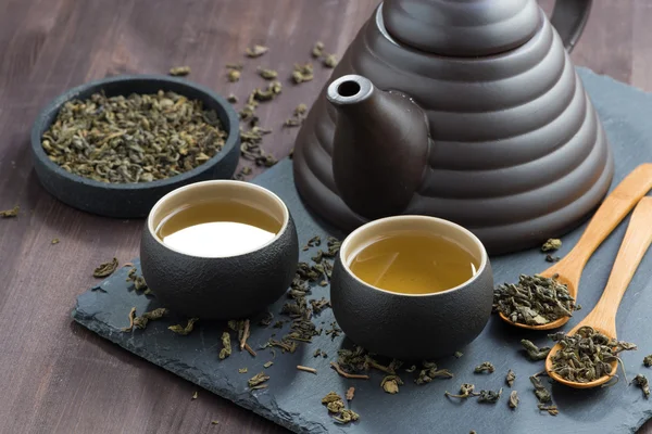 Чайник і чашки зі свіжим зеленим чаєм на дерев'яному столі — стокове фото