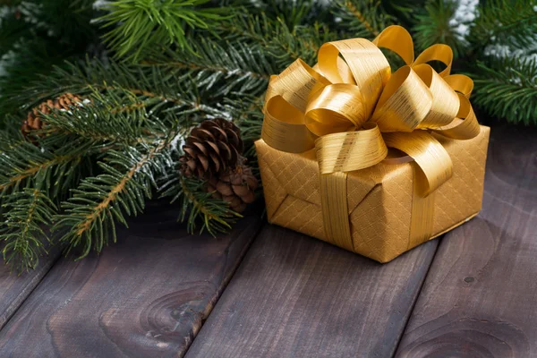 Golden gift box on the background of fir branches — Stock Photo, Image