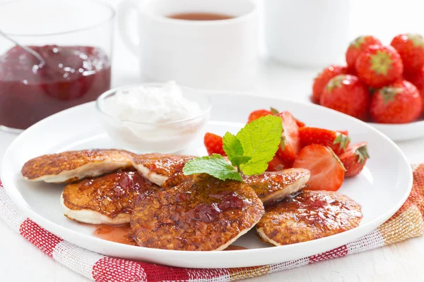 Pancakes with fresh strawberries on a plate, jam and tea — Stock Photo, Image