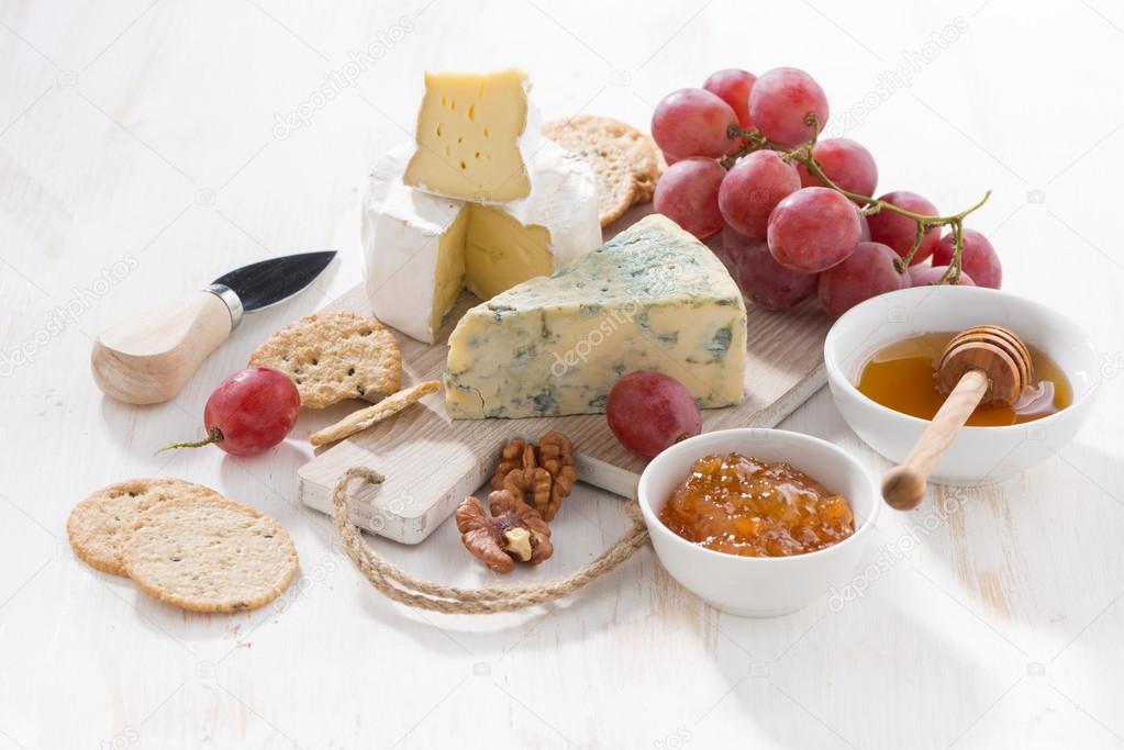 molded cheeses, fruit and snacks on a white wooden background