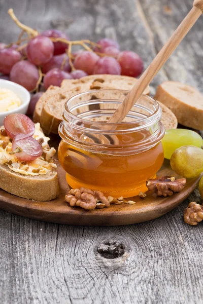 Flavored honey, bread and butter and grapes — Stock Photo, Image