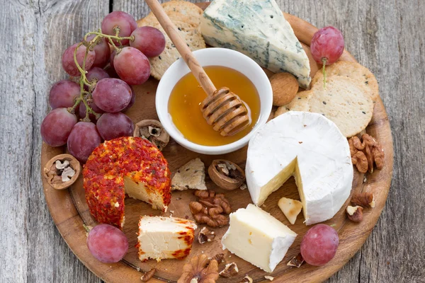 Soft cheeses and snacks on a wooden background, close-up — Stock Photo, Image