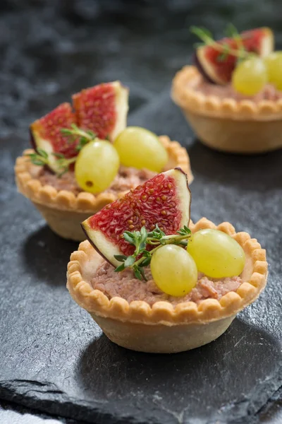 Tartaletas con paté de hígado y fruta sobre un fondo oscuro, vertical —  Fotos de Stock