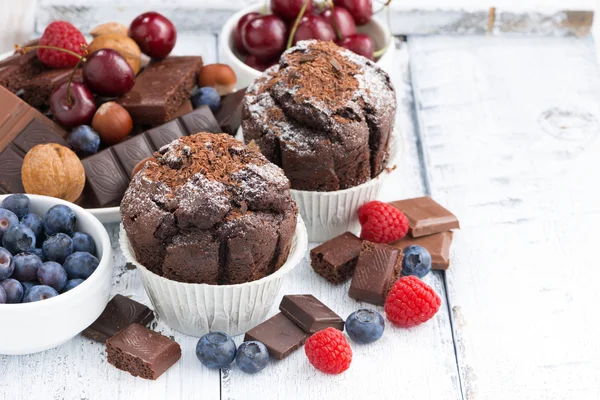 Muffins de chocolate e bagas frescas na mesa de madeira branca — Fotografia de Stock