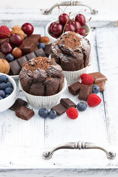 Magdalenas de chocolate y bayas frescas sobre mesa de madera blanca —  Fotos de Stock