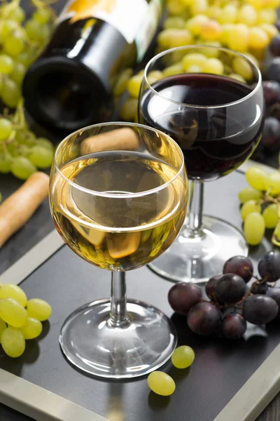 Vinho branco e tinto em copos, uvas no fundo — Fotografia de Stock